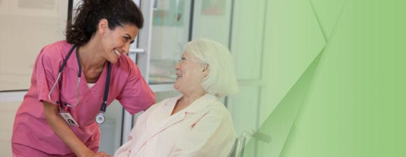 Photograph of a Female nurse standing over a woman sitting in a wheelchair