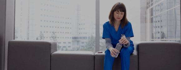 nurse with water bottle sitting in hospital