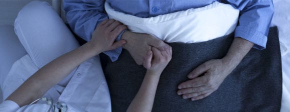 nurse holding older mans hand