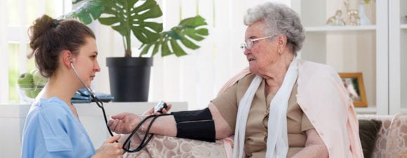 caregiver taking older woman's blood pressure