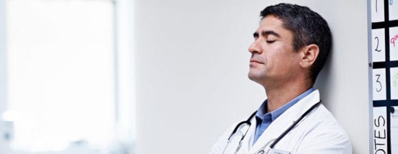 stressed out doctor resting against wall