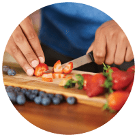 a person cuts fruit on a cutting board