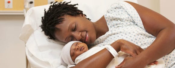 Mom holds her newborn baby to promote healthy pregnancies and safe deliveries.