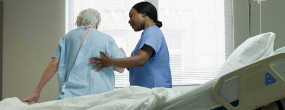 Nurse helps elderly patient at the bedside.