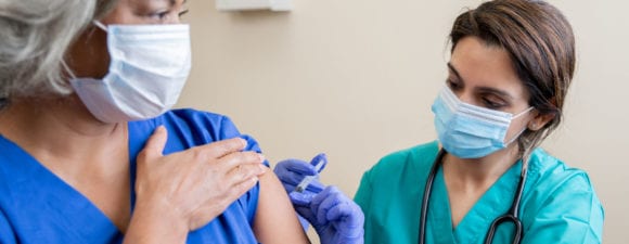 healthcare worker administers healthcare worker with vaccine.
