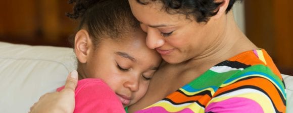 Black woman hugging her young child daughter to help others learn about children's mental health awareness