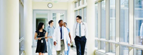 Diverse group of clinicians walking down a hospital corridor