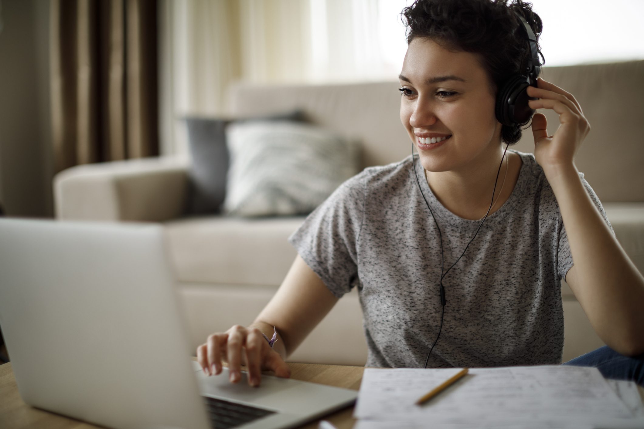 Young woman using laptop and listening to music at home