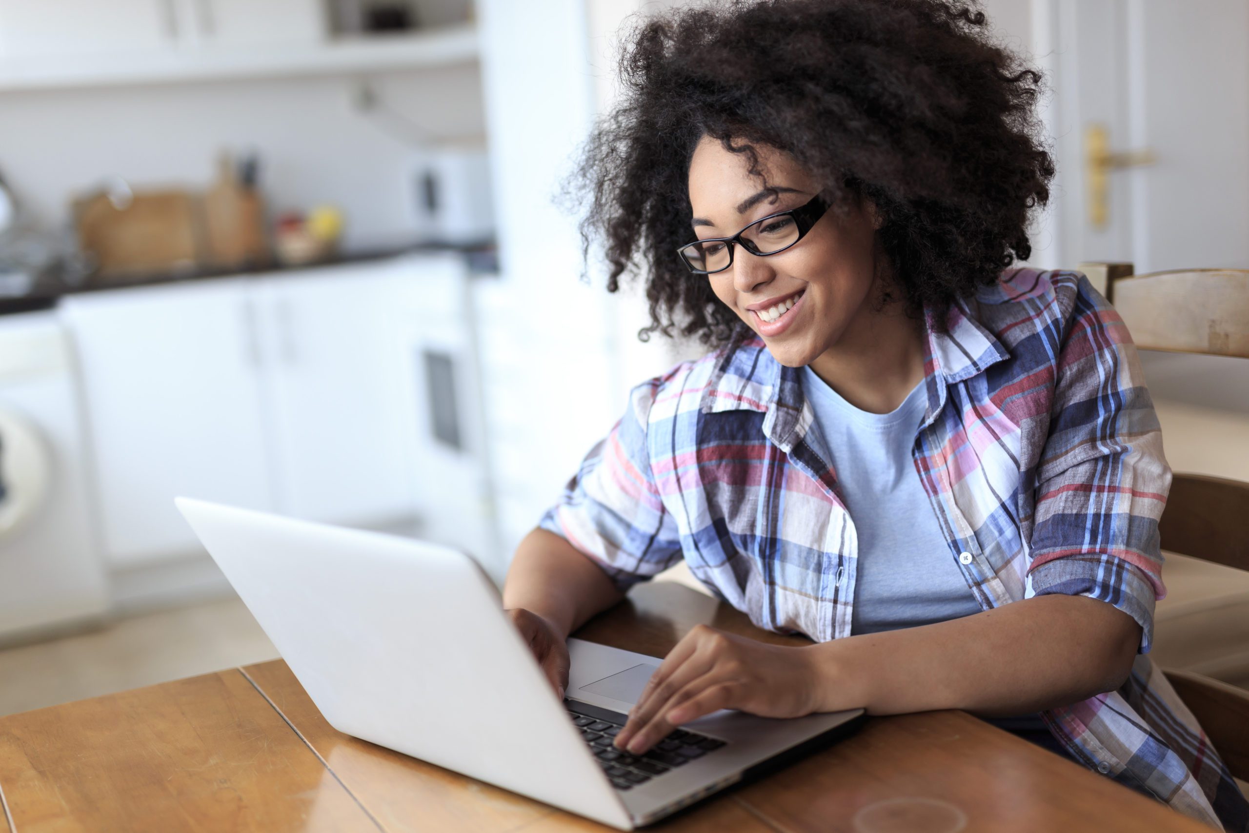 Smiling woman with eyeglasses using laptop at home.