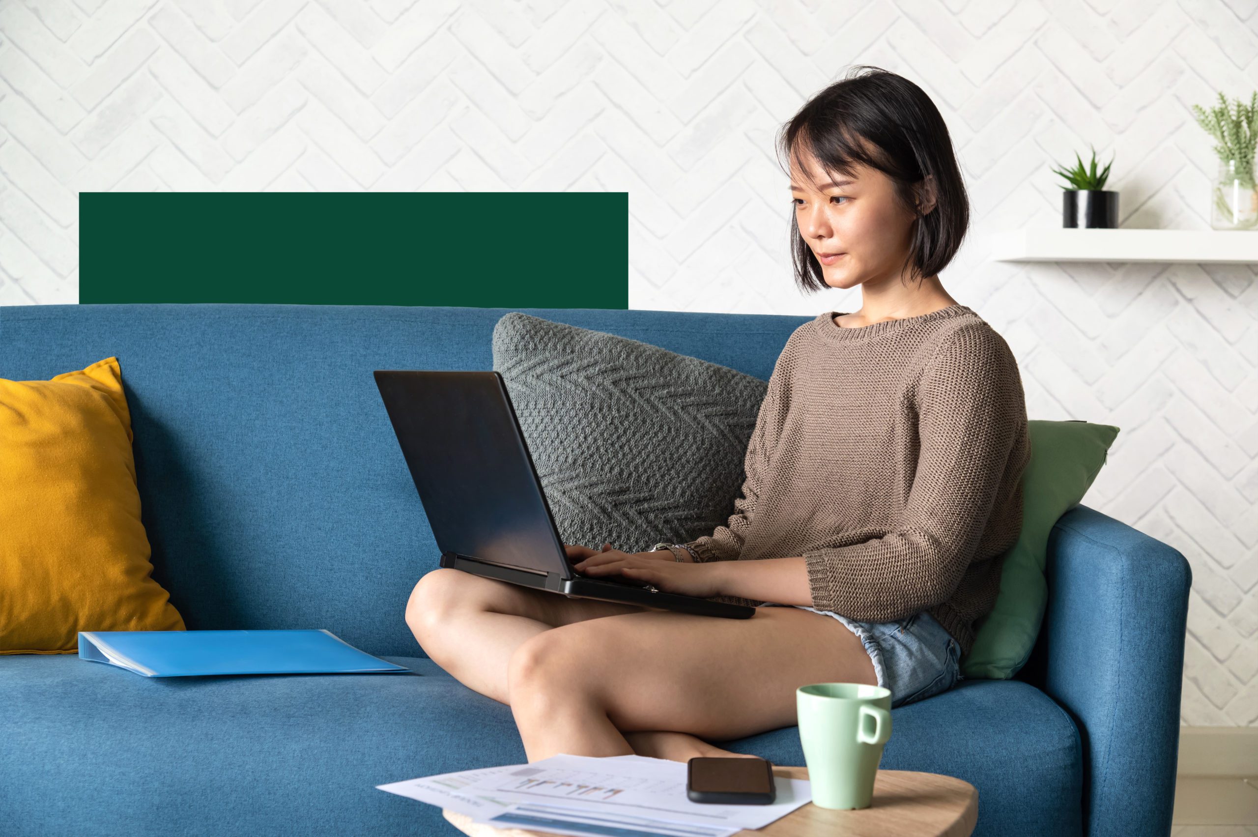 woman sitting on couch working on laptop