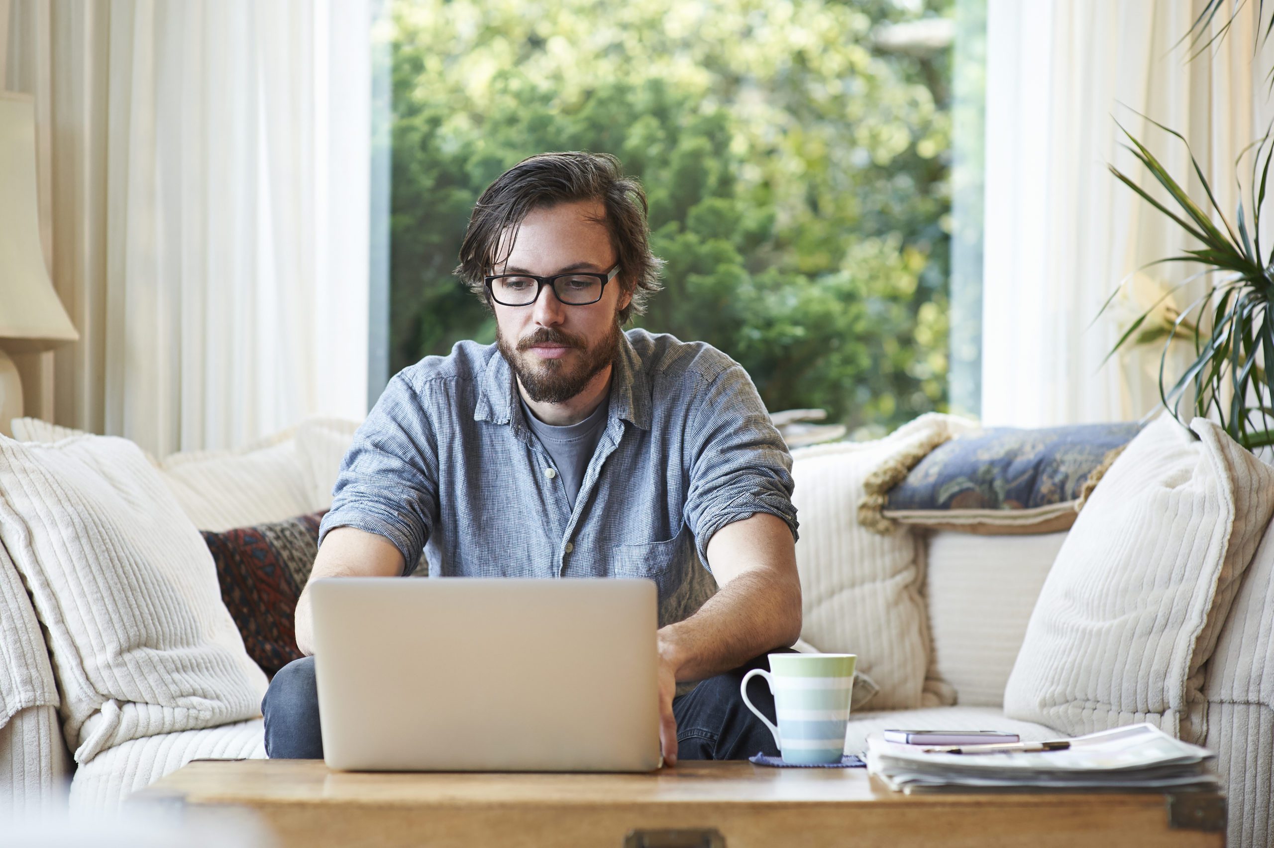 Man sitting on sofa and using laptop at home.