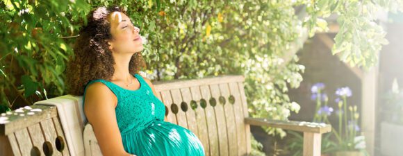 Pregnant woman sits on bench