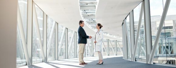 A well dressed man shaking hands with a female doctor