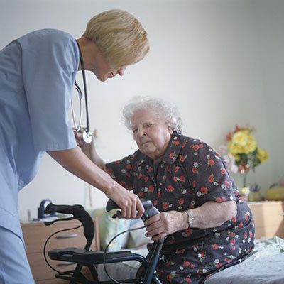 Nurse helping elderly woman stand up.