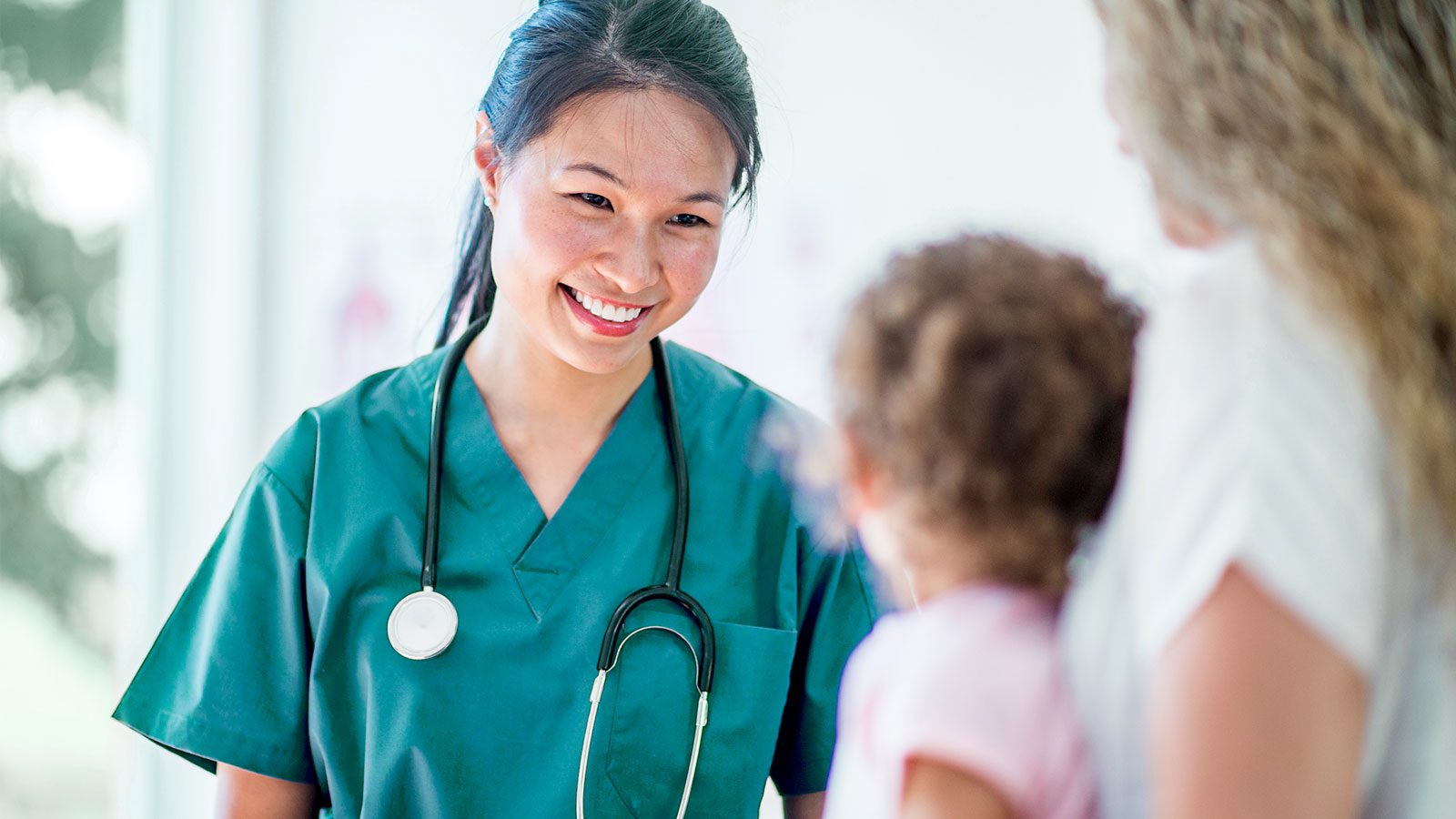 healthcare professional smiles down at young girl