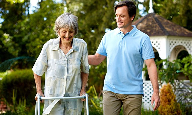 Older woman using walker walking with a young man