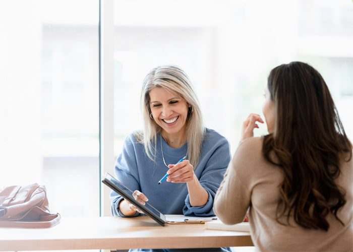 Two women looking at a tablet, discussing how to coordinate whole person care for clients