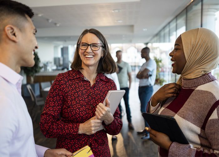 Three smiling coworkers discussing how to start building organizational resilience
