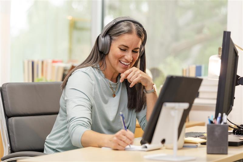 Woman wearing headphones while working on her laptop
