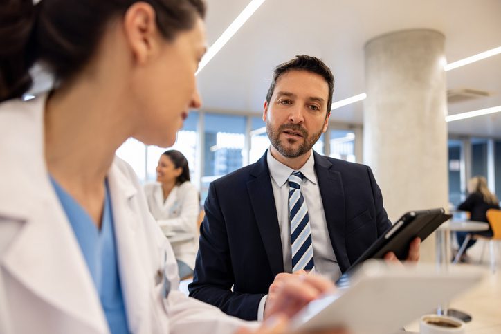 A surveyor interviewing a doctor to ensure they are adhering to Joint Commission National Performance Goals.